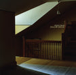 Stairwell with wooden railing and a sign reading 'Yellow House' in a dimly lit room.