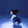 Underwater scene with a person in a blue dress, surrounded by water and light effects.