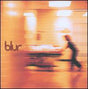 This image features the album cover for "Blur - Blur LP," capturing a moment that seems to encapsulate the blurred, fast-paced essence of the band's music. The cover depicts a hospital corridor with a figure in a gray surgical gown and cap, rushing forward with a sense of urgency.