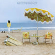 Album cover with a person on a beach, table, chairs, and umbrella with 'Out the Beach' text.