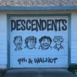 Garage door with 'DESCENDENTS 9th & WALNUT' spray-painted on it.