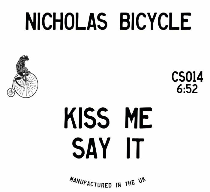 A square white product label or packaging card with bold black text reading 'NICHOLAS BICYCLE' at the top and 'KISS ME SAY IT' in the center. A small black line drawing of a person riding a penny-farthing bicycle appears on the left.