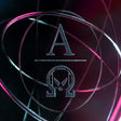 Circular design with a central letter 'A' and another symbol, set against a dark background with pink and blue lighting.