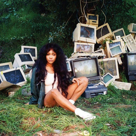Person sitting among old computer monitors and electronic waste in a natural setting