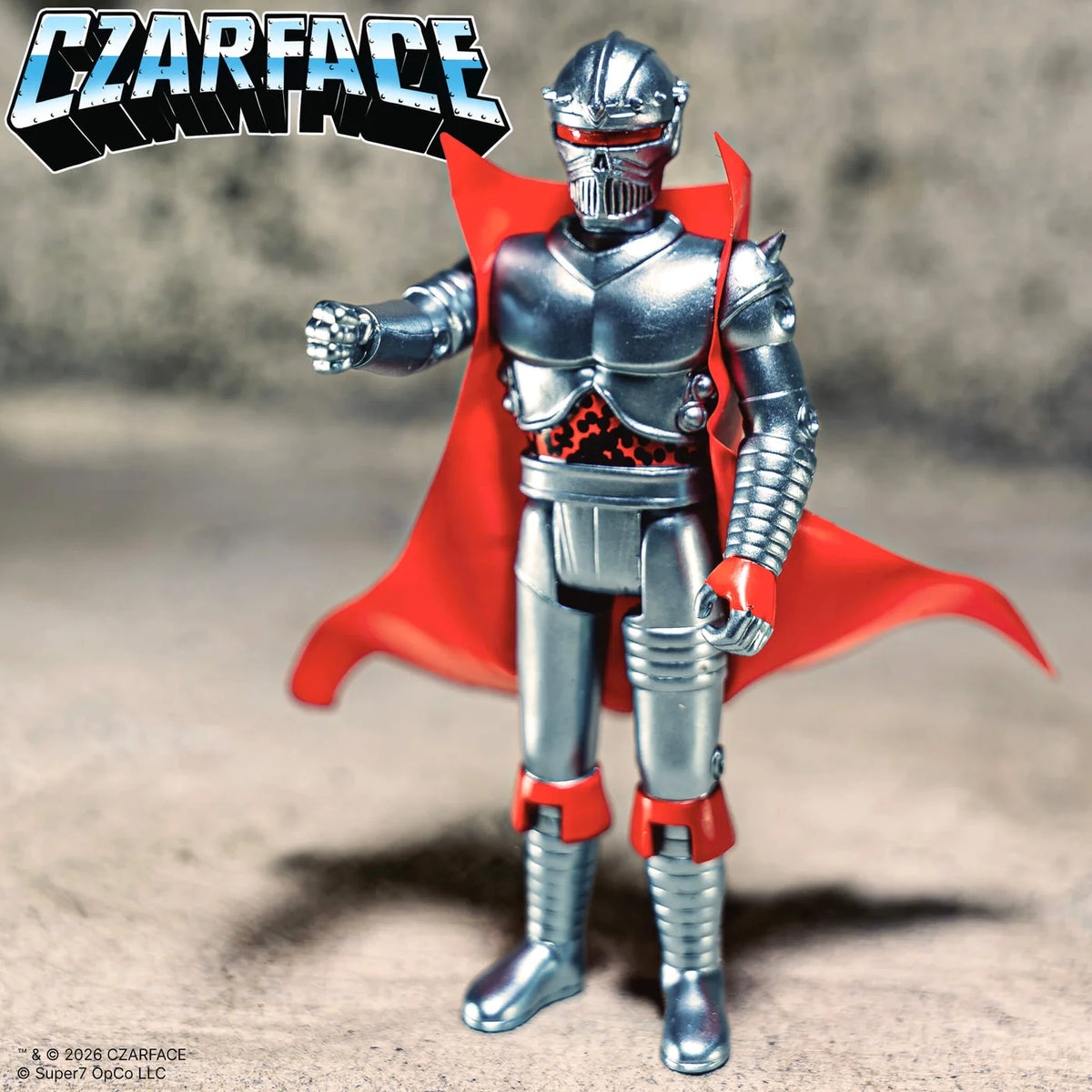 Toy figure in silver armor with a red cape on a textured surface, featuring the 'CZARFACE' logo.