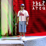 A detailed collectible action figure of a man wearing a baseball uniform and cap, standing on a concrete ledge with a microphone in hand, set against a red roller shutter background with stylized white text in the upper right.
