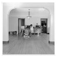 Person sitting at a desk in a room with a chandelier and wooden floor.