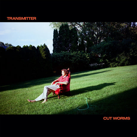 Person sitting in a red chair on grass with trees in the background, album cover for 'Transmitter' by Cut Worms.