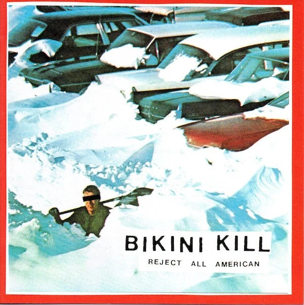Album cover for 'Reject All American' by Bikini Kill featuring a person in a kayak surrounded by snow and cars.