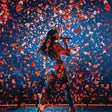 Person on stage with confetti falling around, against a dark blue background