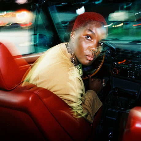 Person sitting inside a car with red interior, blurred lights in the background