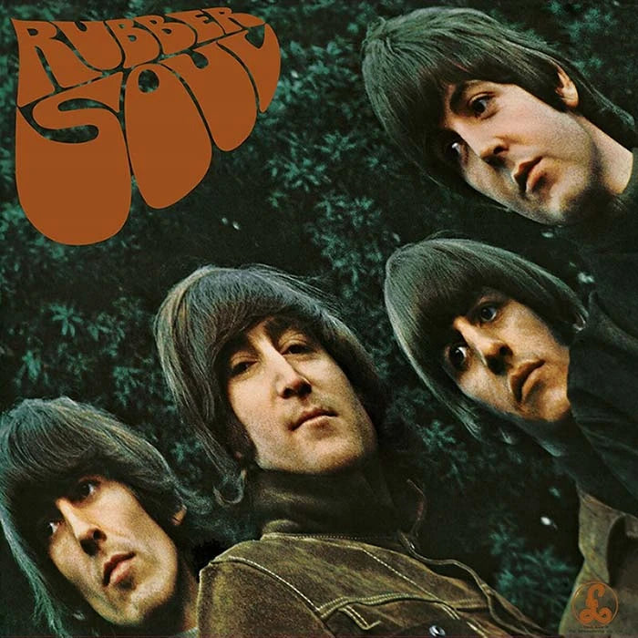The album cover art for 'Rubber Soul' by the band The Beatles, featuring close-up portraits of the four band members against a dark green leafy background with the band's name in a large orange retro font in the top left corner.