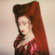 Person wearing a red headscarf and dress with a plain background