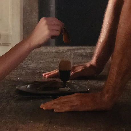 Person applying a product to their leg with a brush on a stone surface.