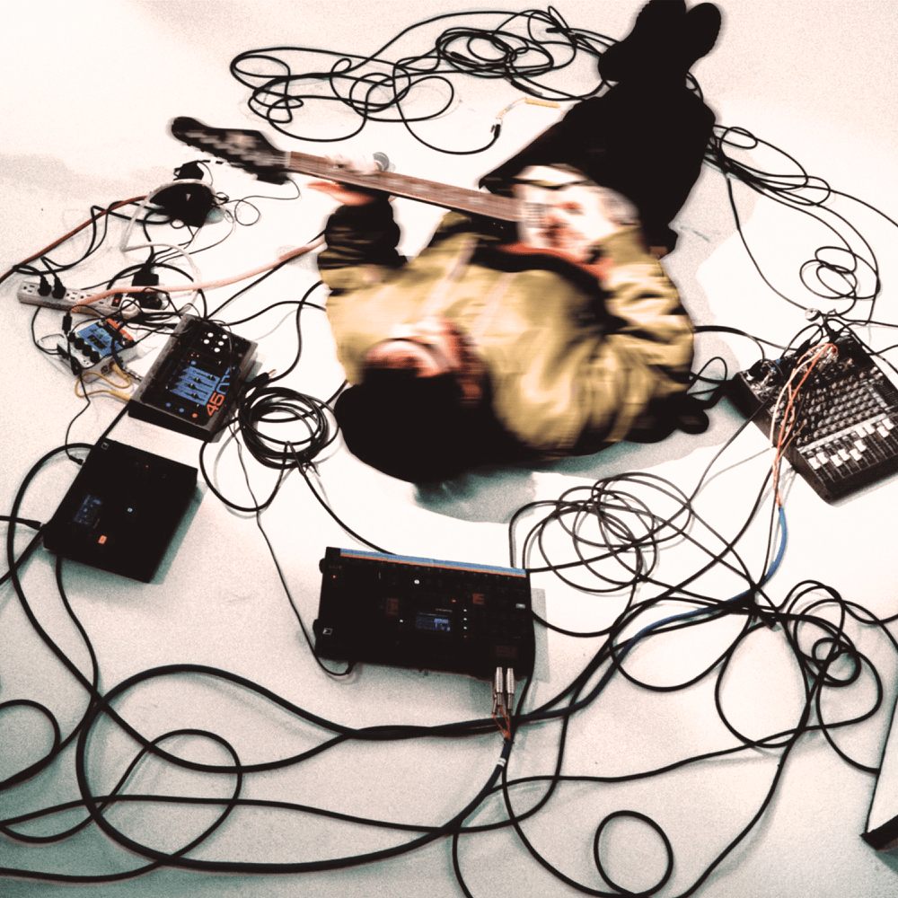 Person playing guitar with electronic equipment and cables on a white background