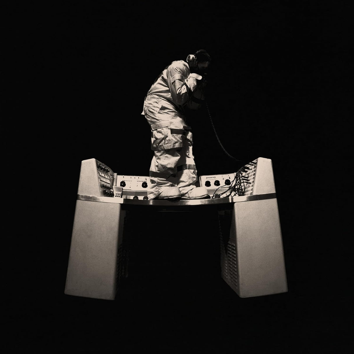 Person in a reflective suit with a helmet on a stand against a black background