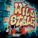 Group of people posing in front of a colorful mural with 'Wild Style' text