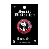 A Social Distortion lapel pin on its original black backing card. The pin is circular with a red border, white gothic text, and a black center featuring a white skull wearing a hat with a cigarette holder.