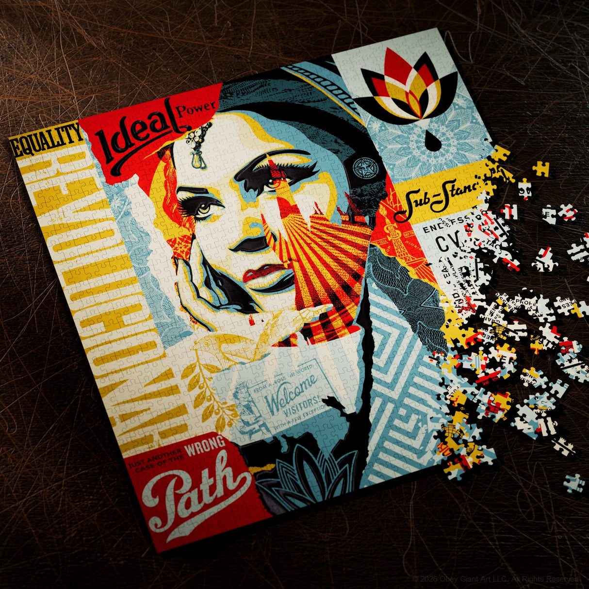 A completed jigsaw puzzle featuring a stylized pop-art portrait with bold red, yellow, blue, and cream sections, shown on a dark textured surface with loose puzzle pieces spilled to the right. Visible text includes 'Equality', 'Ideal Power', 'Wrong Path', and 'Subtlety'.