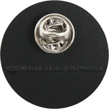 A silver metal pin with a textured, faceted starburst-like center, mounted on a round black backing card.