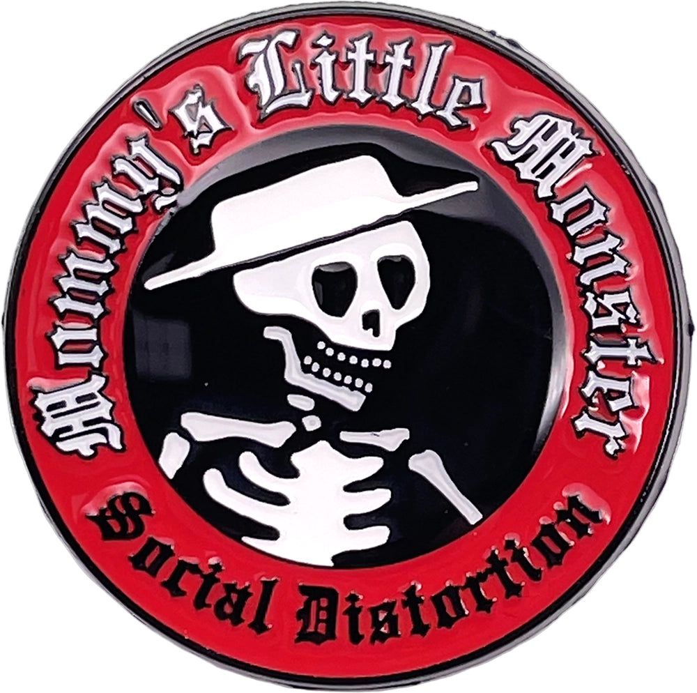 A circular novelty pin or badge featuring a black center with a white skull wearing a white hat, surrounded by a red outer ring with gothic white text reading 'Baby's Little Monster' and 'Social Distortion'.