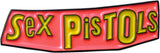 A novelty pin or patch featuring the text 'Sex Pistols' in bold yellow 3D-style lettering on a glossy pink background with a black outline.