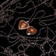 Heart-shaped earrings with a face design on a dark background