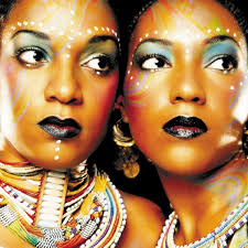 Two women with colorful makeup and jewelry on a black background