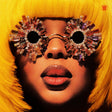 Person wearing sparkling sunglasses and a yellow outfit with a close-up of the face.