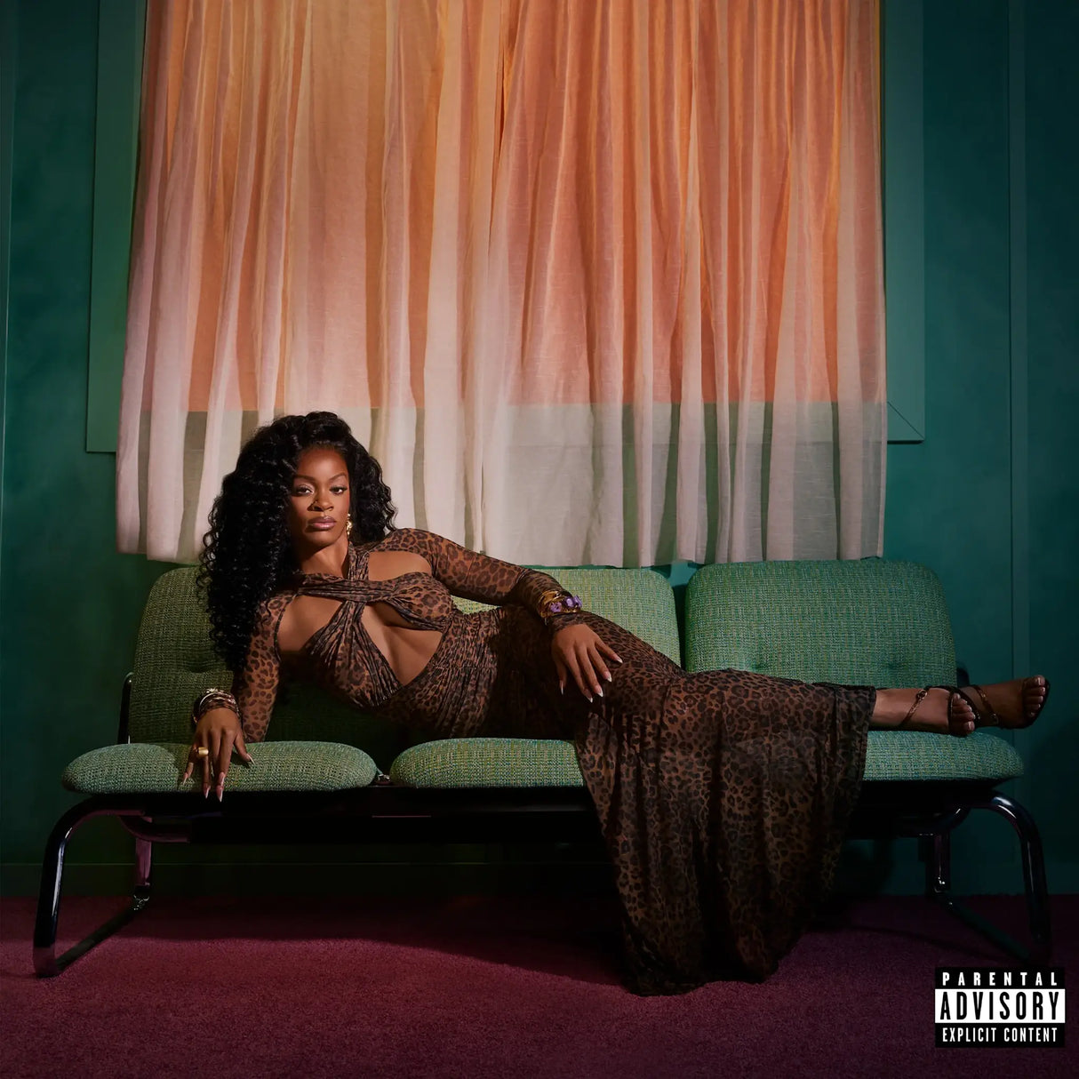 Person in a leopard print outfit sitting on a green couch with aParental Advisory label.