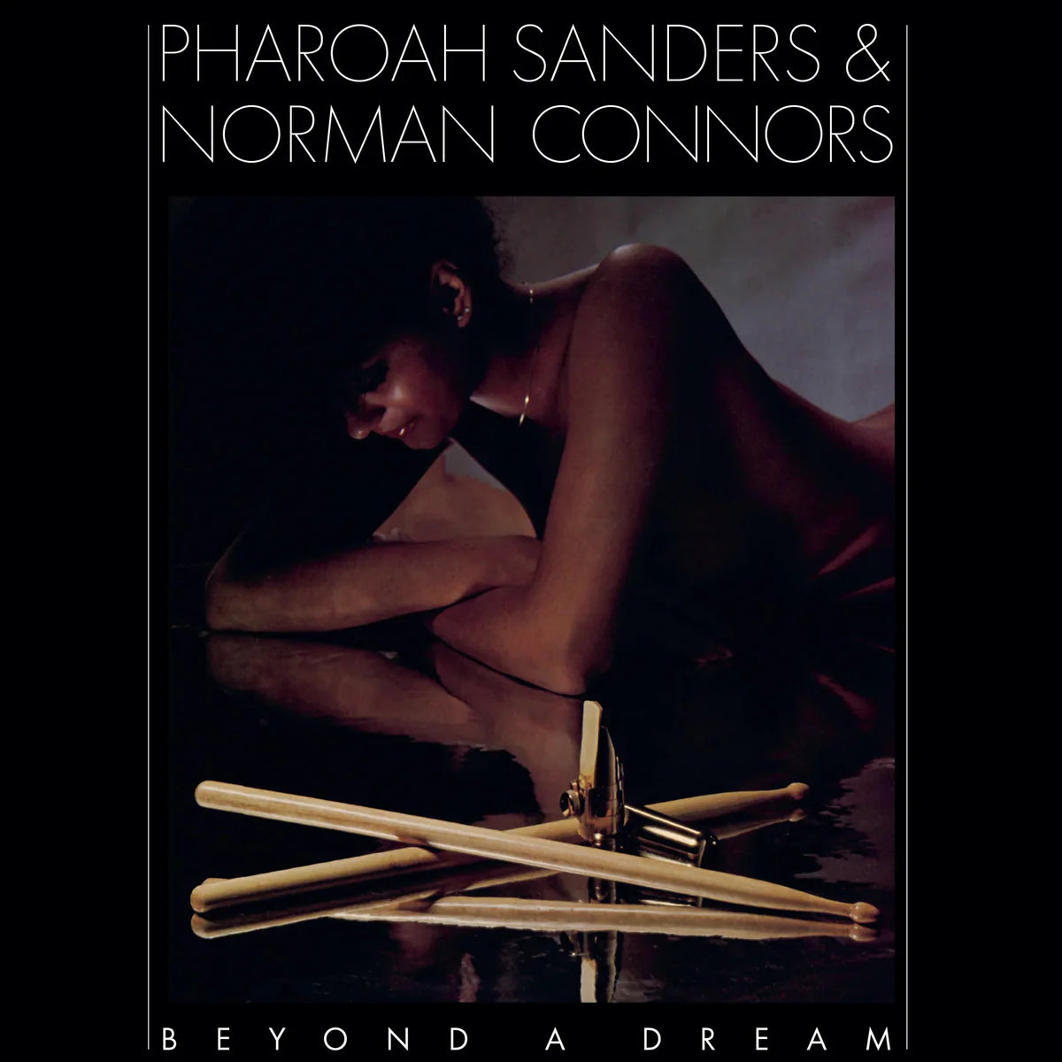 Album cover with a person lying on the ground next to drumsticks, featuring the text 'Pharoah Sanders & Norman Connors Beyond A Dream'.