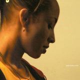 Album cover art for Sade's 'Lovers Rock', featuring a warm-toned close-up profile portrait of a woman against a pale cream background.