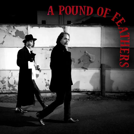 Two men in formal attire walking past a wall with 'A Pound of Feathers' text.
