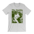 A light gray crewneck t-shirt featuring a green graphic print of the band 'The Smiths' with a photo of a child and the quote 'There is a light that never goes out'.