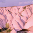 A landscape with pink and orange hoodoos under a blue sky