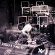 Black and white album cover featuring a photograph of Elliott Smith with musical equipment and records. The album title 'xo' is prominently displayed.