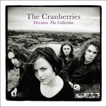 The Cranberries band members in black and white photo, with Dolores O'Riordan in the foreground and the band in the background, titled 'Dreams The Collection'.