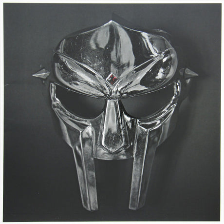 A black and silver mask with a stylized face design, possibly representing a character or concept from a music or film.