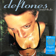 This image features the album cover for the Deftones album "Around The Fur." The cover artwork is striking with its dark, blurred portrait of a woman's face, set against a muted background that includes hints of greenery and a blue text overlay indicating the album title and tracklist.