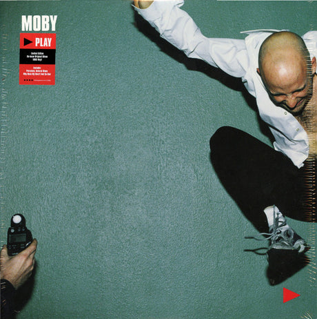 The image shows the album cover of 'Moby - Play 2LP'. It features a photograph of a person in a dynamic pose with arms extended, wearing a white shirt and black pants.