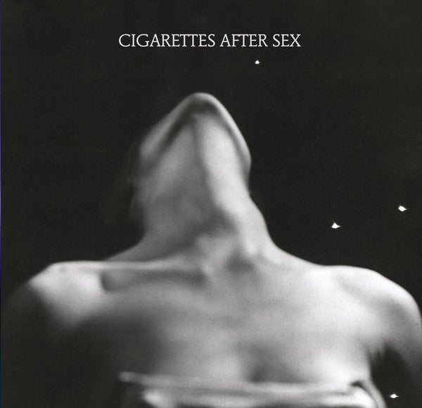 This image features the album cover for "Cigarettes After Sex - EP I," encapsulating a moody and enigmatic atmosphere. The artwork displays a blurred, abstract figure set against a dark background with subtle star-like dots adding a hint of texture.