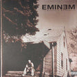 Album cover of Eminem's 'The Marshall Mathers 180g 2LP' featuring a black and white image of a man sitting on a wall beside a house.
