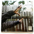 A vinyl record album cover featuring a person's hands reaching towards a wooden fence with a blurred background.