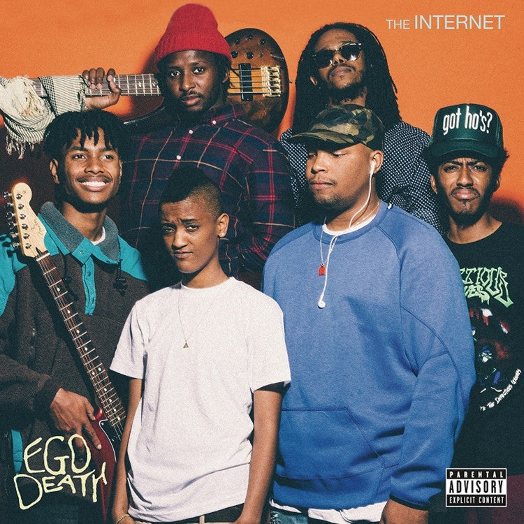 The Internet band members posing for a group photo with an orange and yellow tinted background. The band consists of various members, with the central figure being a woman, likely Syd, the lead singer.